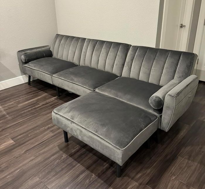 A gray L-shaped sectional sofa with an extended chaise lounge placed on wooden flooring