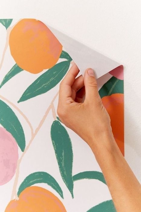 A hand demonstrating the ease of peeling back the removable wallpaper