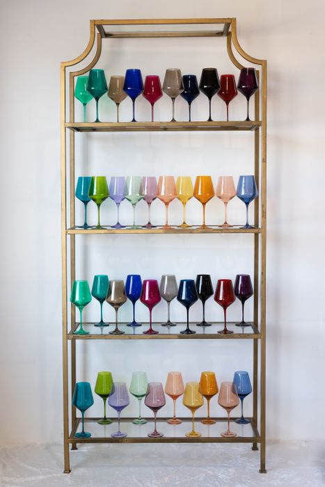A shelf showcasing a collection of perfectly shaped glasses, each in solid hues that gradually change color from top to bottom, creating a stunning gradient effect