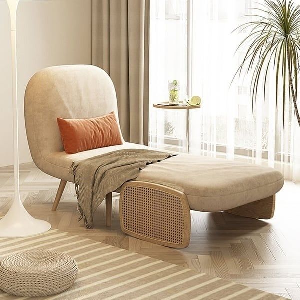 A modern-style lounge chair with an ottoman and side table adorned with plants, placed in a bright, airy room