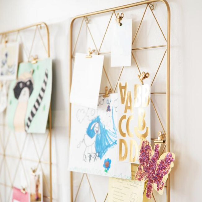 A gold wire frame with triangular designs and clips holding up pictures and cards