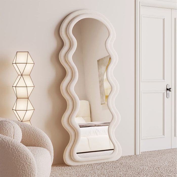 The wavy mirror is displayed leaning elegantly against a wall.