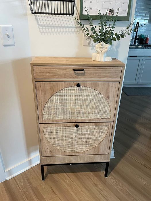A wooden cabinet featuring circular rattan-inlaid doors and a top drawer, elegantly placed in a kitchen environment