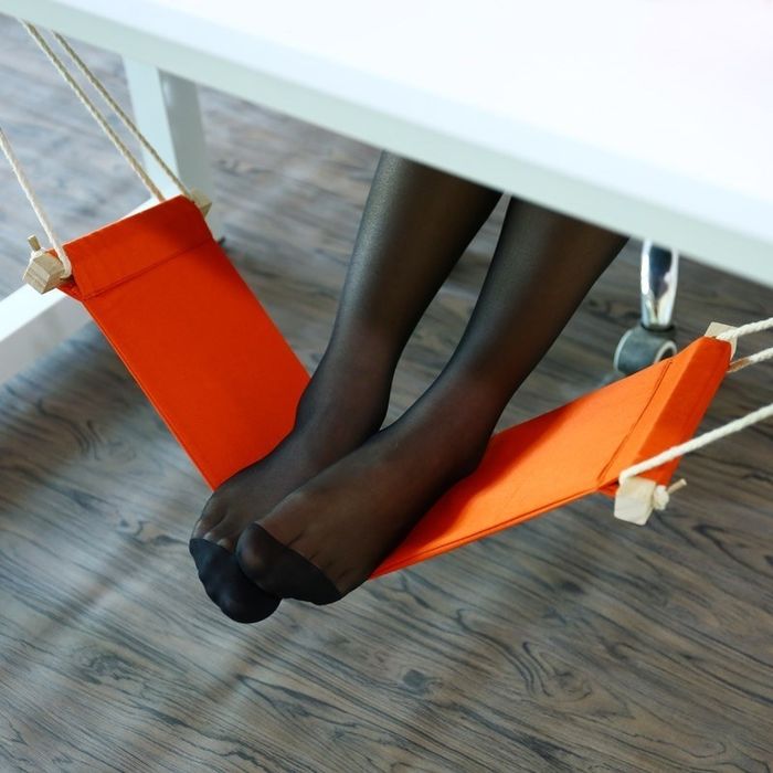 A model relaxing with a foot hammock set up under their desk.