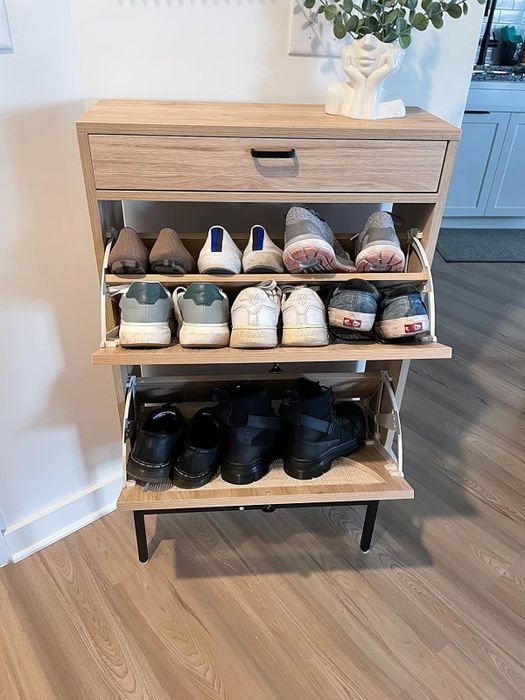 Wooden shoe cabinet with three open shelves neatly displaying a variety of shoes in a cozy home setting