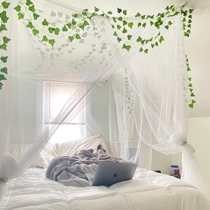 A reviewer's bedroom featuring a white canopy, faux vines, and stylish bedding