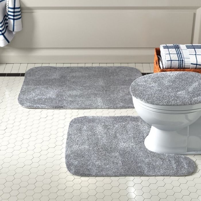 A gray bath rug set arranged in a bathroom.