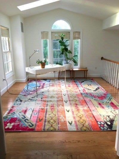A minimalist office featuring a large, colorful rug on the floor
