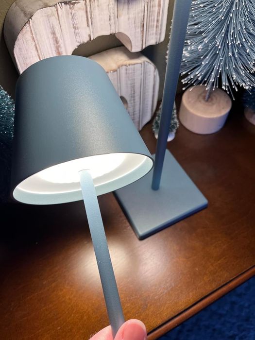 A person adjusting a modern desk lamp, ideal for both office and home decor shopping articles