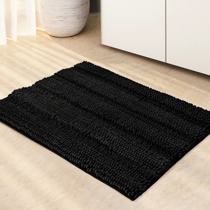 A black microfiber bath rug placed in a bathroom.