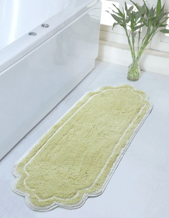 The soft light green mat placed in front of a bathtub.