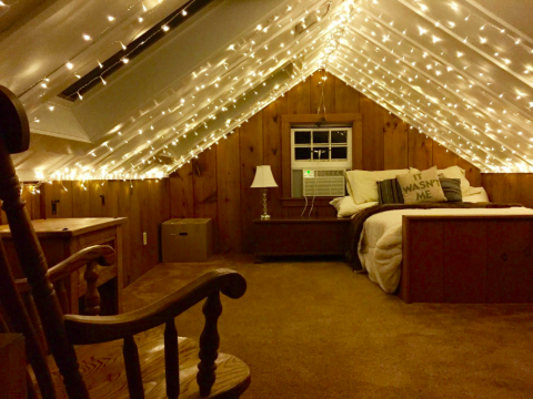 A reviewer's photo of lighted curtains draped across an A-frame ceiling in an attic bedroom