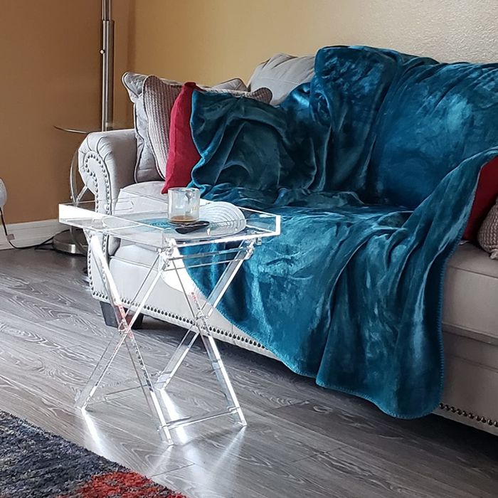 A reviewer's lucite tray table is shown positioned in front of a sofa