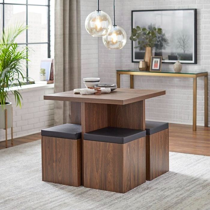A similar dining set with a table and four stools that can be tucked in to save space, each stool padded for comfort.