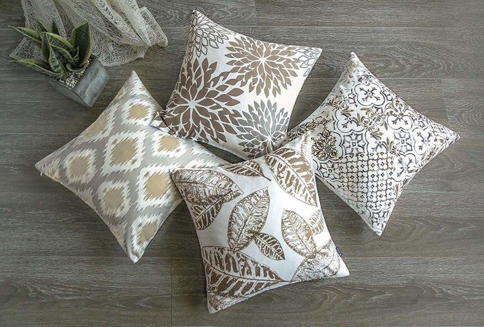 four pillows in white with grey, brown, ikat, floral, leaf, and trellis patterns