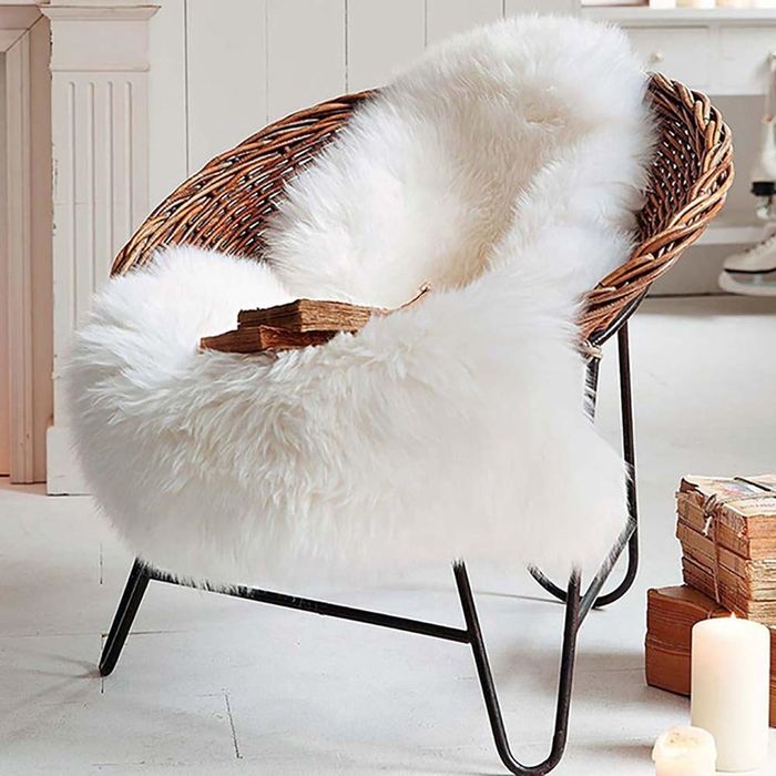 A white faux-sheepskin rug placed on a wicker armchair.