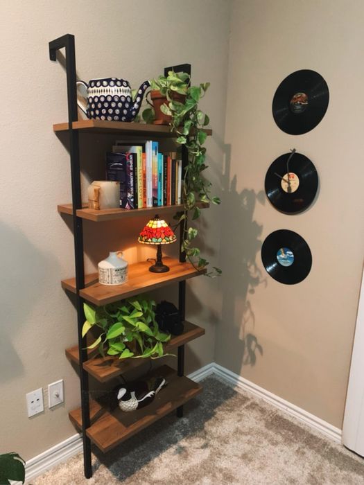 Another reviewer's oak and black 5-tier shelf displaying various plants, books, and knickknacks