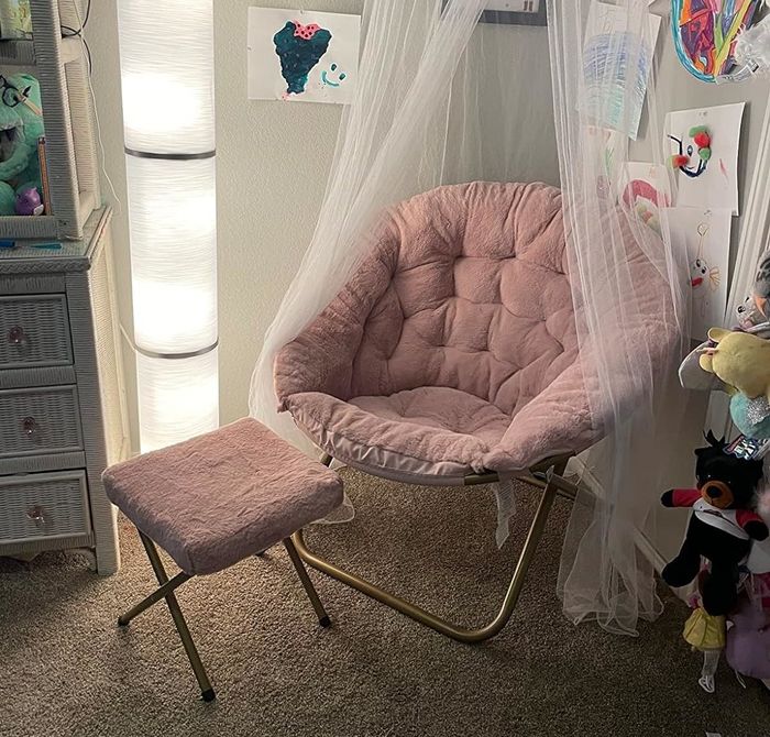 A snug reading corner featuring a soft round chair, a tiny stool, and a floor lamp, decorated with children's artwork