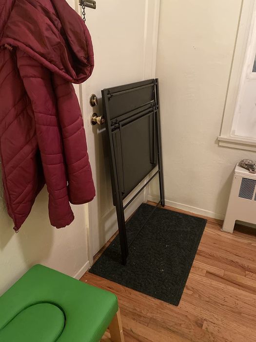 Another reviewer's folded black desk leaning against a wall
