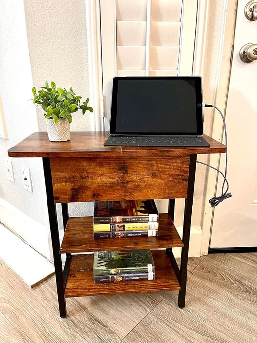 A reviewer’s wooden side table with shelves, featuring books, a potted plant, and a tablet for a well-organized and stylish look.