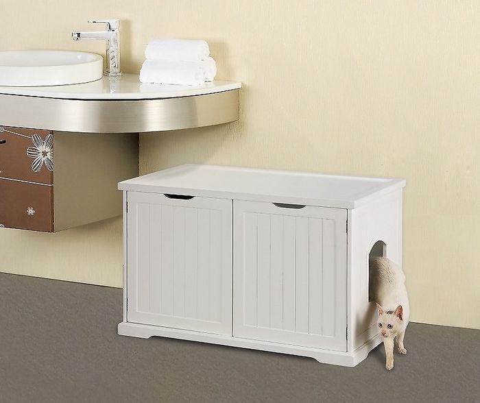 A small white cabinet with two doors that fits under a sink, with a cat emerging from the side entrance.