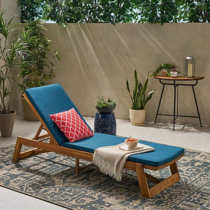The chaise in teak/blue with a decorative pillow.