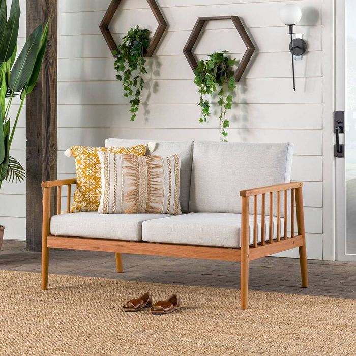 The loveseat in a natural color, accented with decorative pillows.