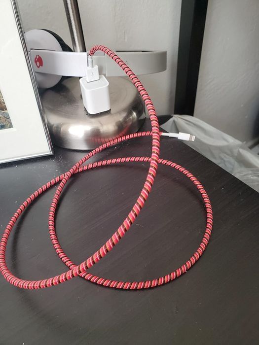 A reviewer's phone charger wrapped in a red protective sleeve