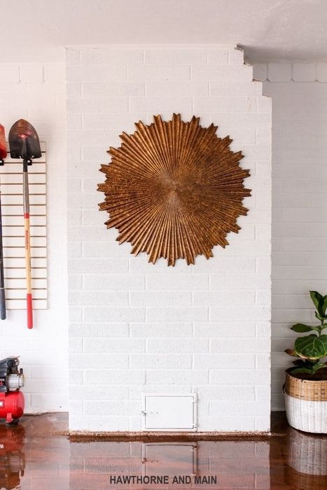A cinderblock garage now painted white and rejuvenated, with an abstract sun-like sculpture hanging on the wall to add flair.