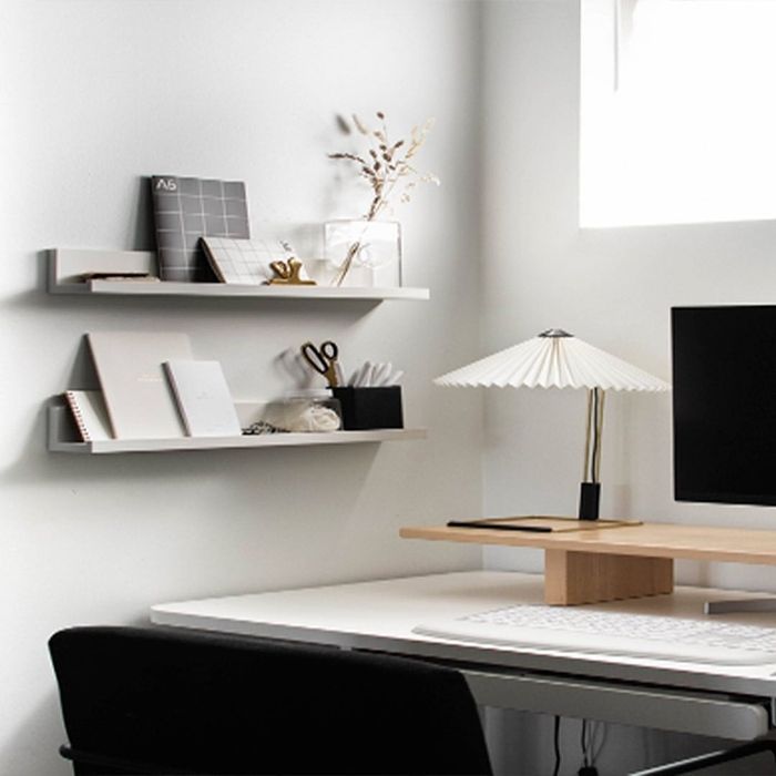 An office area with L-shaped shelves decorated with a pen cup, notebooks, and a flower vase.