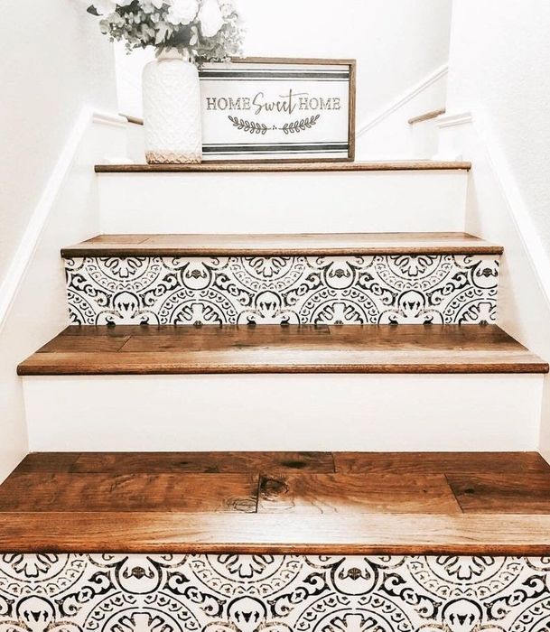 White stairs with dark wood treads; every other stair riser is adorned with a faux-distressed black geometric pattern on white.