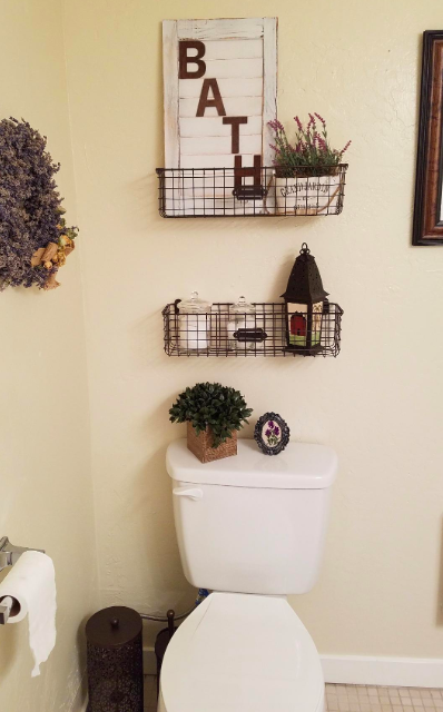 Shallow wire grid baskets are mounted above a toilet, holding various decorative items inside.