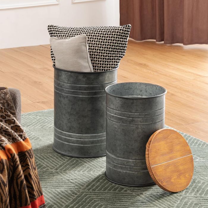 Two metal storage bins with wooden lids removed, revealing blankets and pillows inside