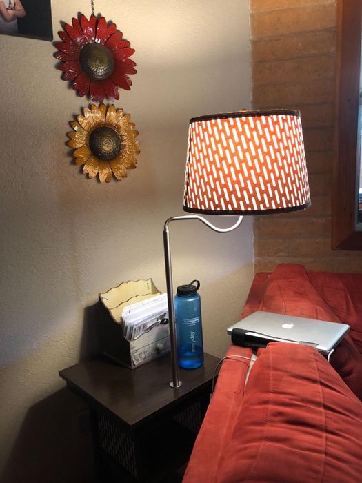 Another reviewer’s side table with an attached lamp, placed behind a red sofa, adding both style and functionality to the space.