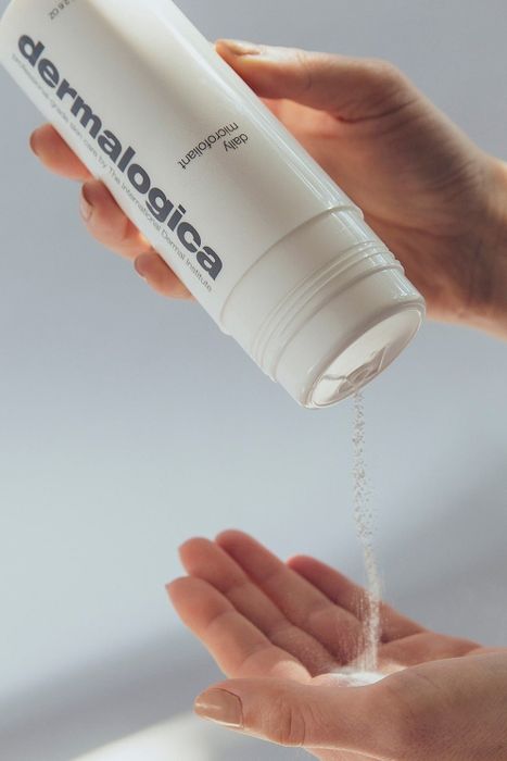 Model pouring the product from a white bottle into their hand.