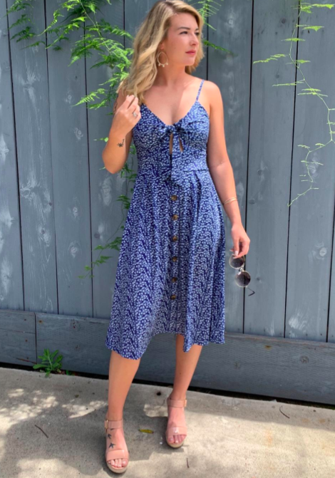 A reviewer in a blue and white floral dress