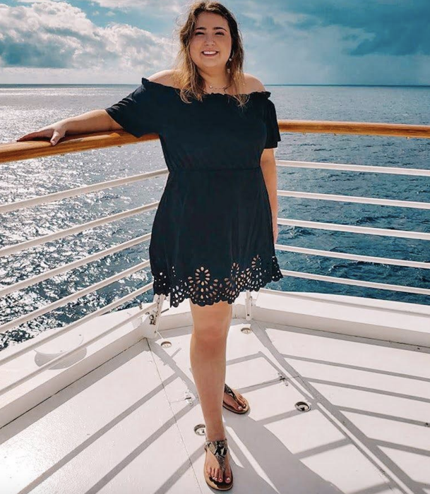 A reviewer showing off the black off-shoulder dress.