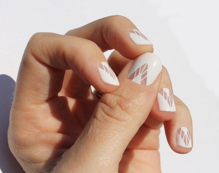 hands displaying a manicure with nail wraps featuring a sleek white geometric pattern