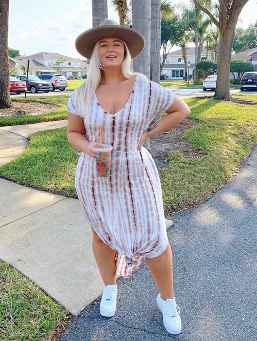A reviewer wearing a dress tied in a knot to shorten its length