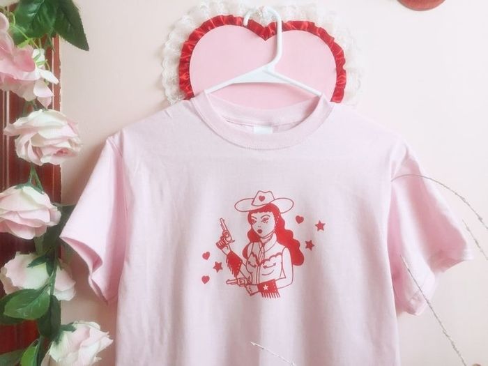 a pink t-shirt featuring a stylish cowgirl illustration