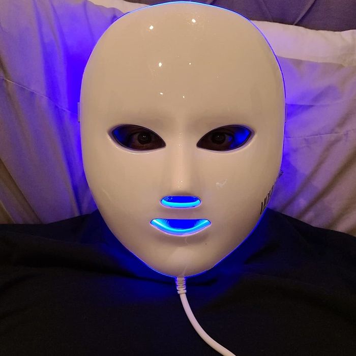 A reviewer wearing the mask with the blue LED light activated.