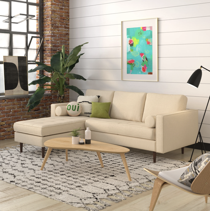 A beige sectional sofa with walnut-colored wooden legs is showcased in a living room setting.