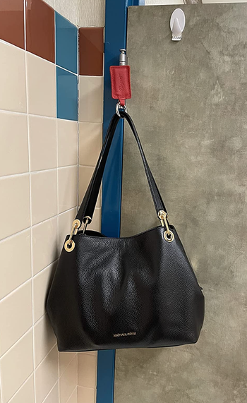 A reviewer's purse magnetized to the hinge of a bathroom door.