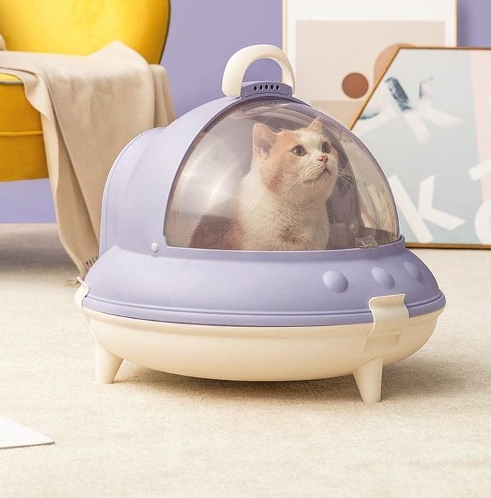 A cat sits inside a purple UFO-style litter box.