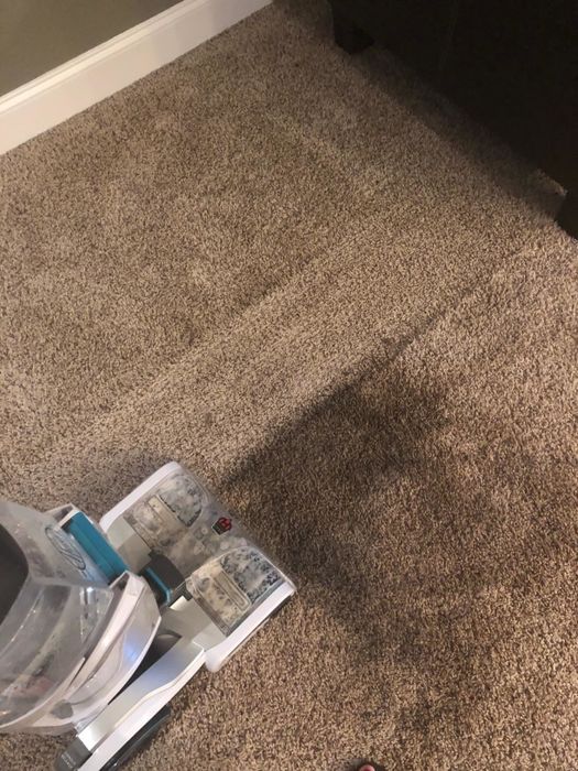A reviewer demonstrating the Hoover on their carpet, with a visible contrast between the cleaned area and the remaining mess