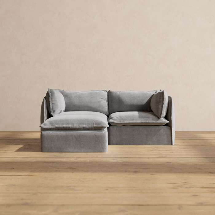 Compact gray sectional sofa with soft cushions, placed on a wooden floor—perfect for small living rooms