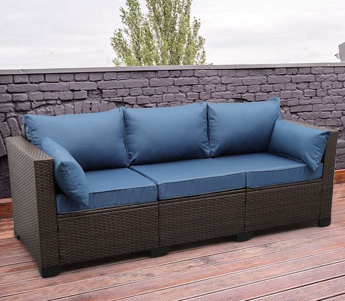 The blue sofa with a black frame is displayed on a wooden deck
