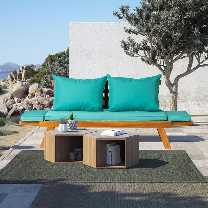 Outdoor seating with turquoise cushions on a wooden bench, paired with a modern hexagonal coffee table adorned with plants and magazines.