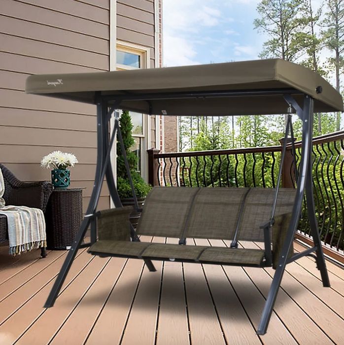 A dark green freestanding porch swing placed on a charmingly decorated porch.