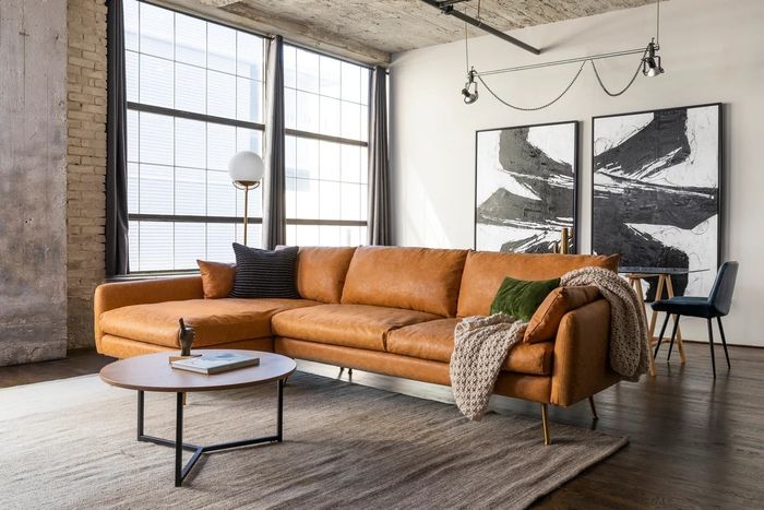 A tan faux leather sectional is displayed in a stylish living room setting.